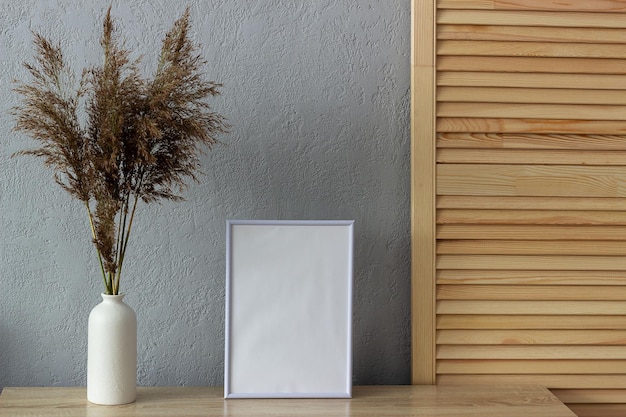 Cornice per foto in bianco per mockup di decorazioni per la casa vicino al muro di cemento verniciato grigio Posto per il testo