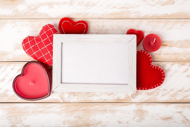 Cornice per foto tra decorazione romantica di San Valentino con cuore e candela su un tavolo di legno bianco