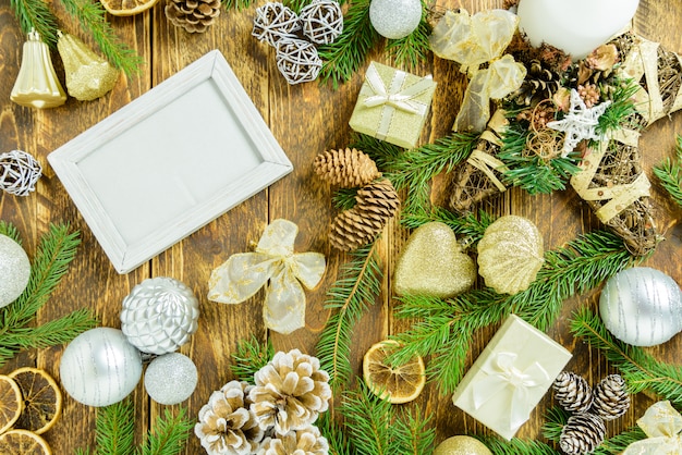 Cornice per foto tra decorazioni natalizie, con diversi ornamenti di colore bianco su un tavolo di legno marrone. Vista dall'alto, cornice per copiare lo spazio.
