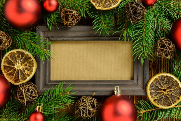 Cornice per foto tra decorazioni natalizie, con palline rosse su un tavolo di legno marrone. Vista dall'alto, cornice per copiare lo spazio.