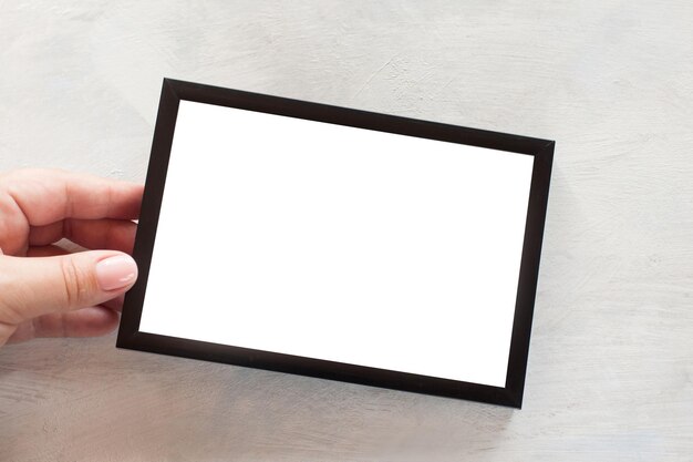Cornice per foto vuota che tiene in mano su sfondo bianco Concetto di saluti di tendenza e ricordi di famiglia vicino all'immagine con spazio per la copia