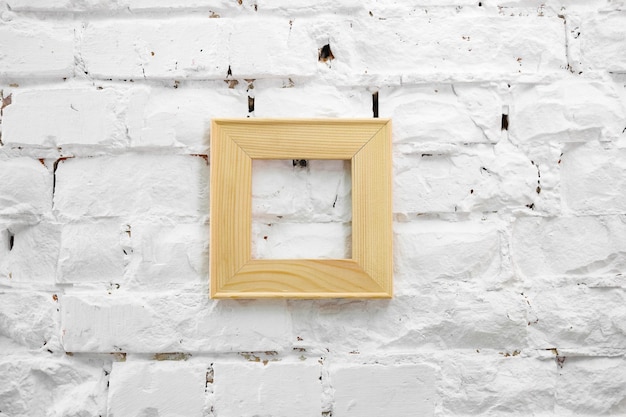 Cornice quadrata di legno su una parete di mattoni bianchi