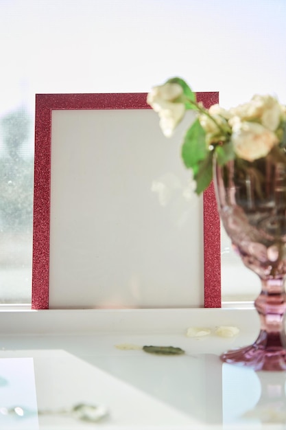 Cornice rosa con luce solare e bicchiere di vino con rose bianche Messa a fuoco selettiva Foto di alta qualità