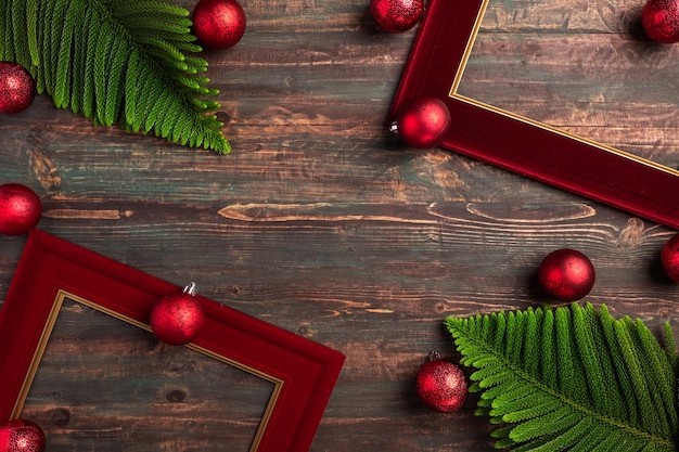 Cornice rossa natalizia con foglia di pino e decorazioni a pallina su tavola di legno