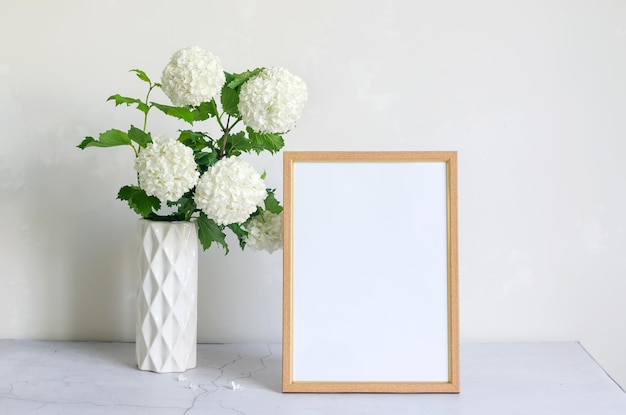 Cornice vuota e bouquet di ortensie di fiori bianchi in un vaso su sfondo grigio