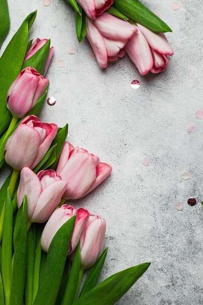 Cornici di fiori. tulipani rosa su sfondo grigio pietra. concetto di biglietto di auguri. modello. flatlay con copia spazio.