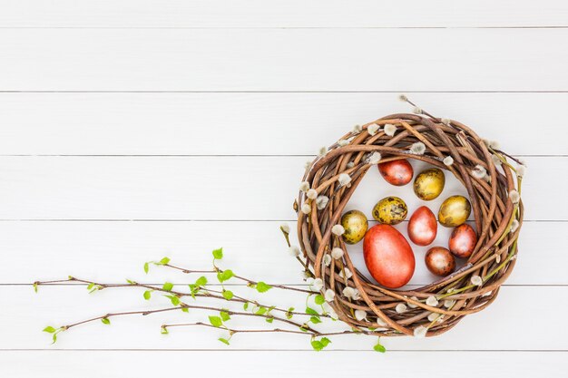 Corona del salice di Pasqua, uova di Pasqua, rami di betulla su fondo di legno bianco