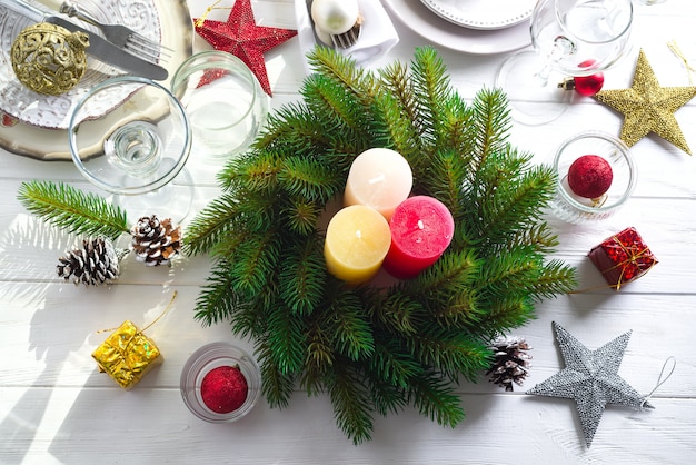 Corona di Natale con grandi candele colorate su un tavolo con un ambiente natalizio