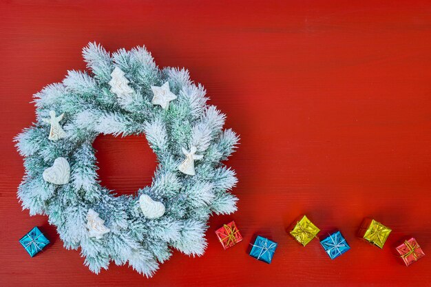 Corona di natale con la decorazione su colore rosso.