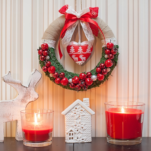 Corona di Natale decorata con bacche rosse e fiocco di nastro rosso