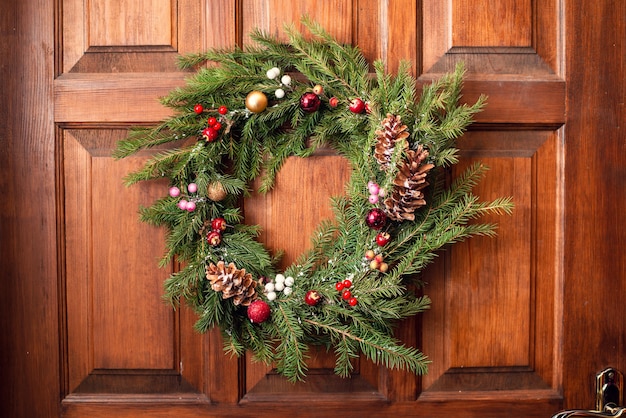 Corona di Natale sul primo piano all'aperto della porta di legno