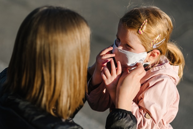 Coronavirus il concetto finale. Non più covid-19. Bambina, madre indossare maschere a piedi sulla strada. La mamma rimuove la maschera bambino felice. Famiglia con bambino all'aperto. festeggiare il successo. Pandemic è finita, è finita.