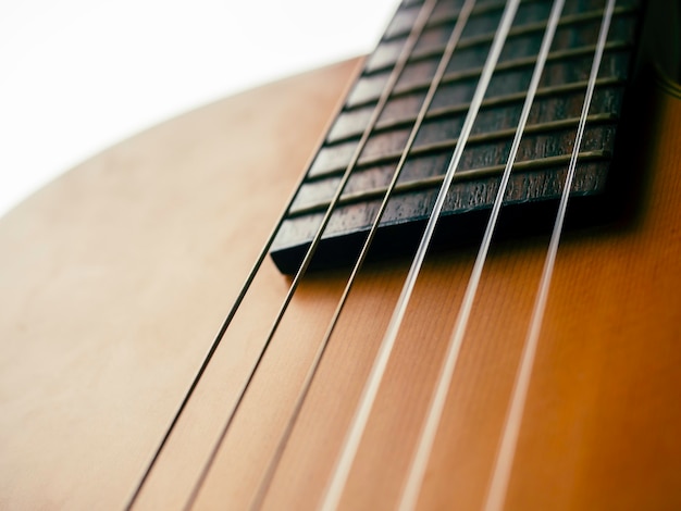 Corpo della chitarra acustica senza sfondo della buca. Primo piano di sei corde sulla tastiera e tasti sulla chitarra classica elettrica in legno marrone.