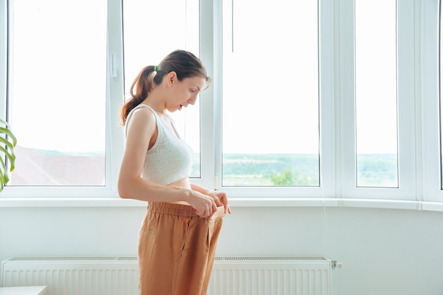 Corpo di donna felice sorpreso sottile in pantaloni grandi Risultati di una dieta sana a casa