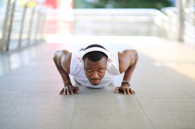 Corpo di esercizio afroamericano dell'uomo sul pavimento ad all'aperto