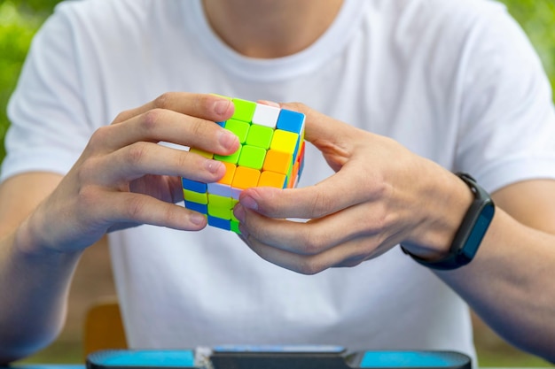 Corpo ritagliato di bambino, nelle cui mani giace un puzzle meccanico multicolore che sta cercando di risolvere