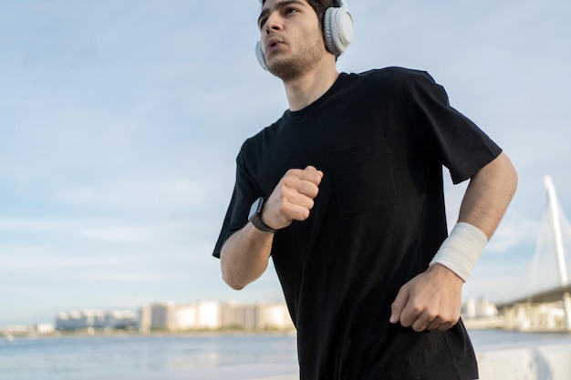 Correre in abbigliamento sportivo e cuffie Un corridore maschio si allena all'esterno