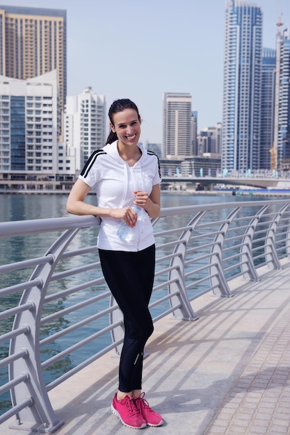 Correre nel parco cittadino. Donna corridore fuori jogging al mattino con la scena urbana di Dubai in background