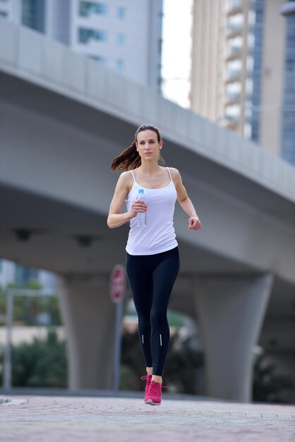 Correre nel parco cittadino. Donna corridore fuori jogging al mattino con la scena urbana di Dubai in background
