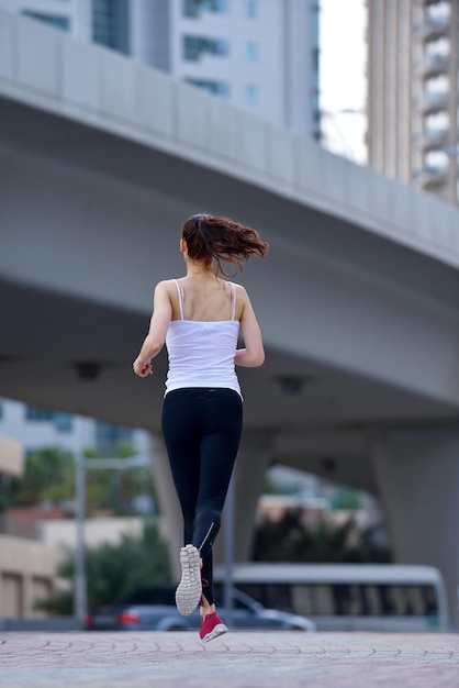 Correre nel parco cittadino. Donna corridore fuori jogging al mattino con la scena urbana di Dubai in background