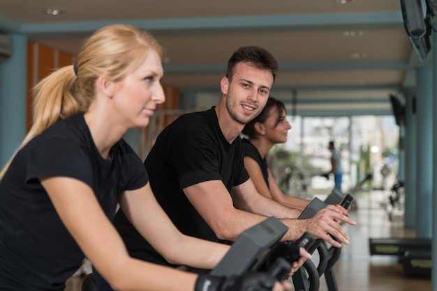 Correre sul tapis roulant in palestra o in un gruppo di fitness club di donne e uomini che si esercitano per ottenere più forma fisica