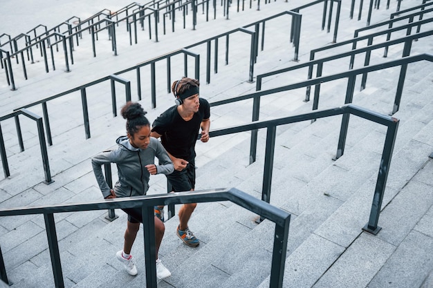 Correre sulle gradinate L'uomo europeo e la donna afroamericana in abiti sportivi si allenano insieme