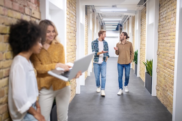 Corridoio dell'ufficio. Ragazze che guardano gli uomini che arrivano dall'altra parte del corridoio