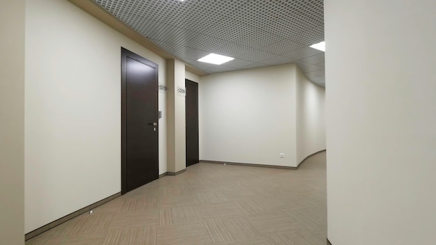 Corridoio rotondo vuoto con pareti beige chiaro e porte chiuse marrone scuro porte chiuse lungo un illuminato