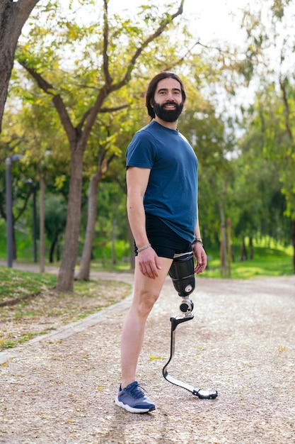 Corridore allegro con una protesi della gamba atletica in piedi su un sentiero circondato da alberi