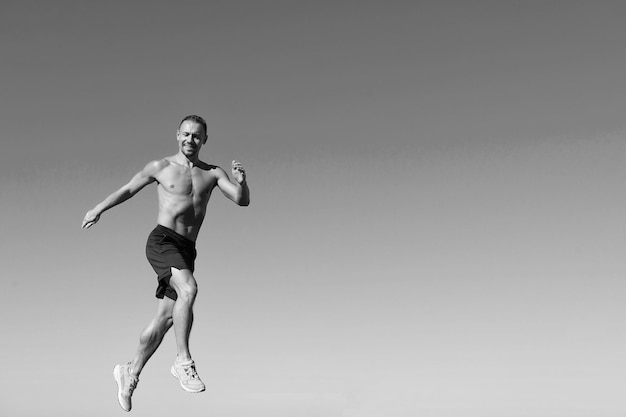 Corridore allenamento mattina durante l'alba Sport motivazione Corri sana abitudine Corridore movimento avanti cielo sfondo copia spazio Mattina corsa riempire di energia Uomo atleta torso muscolare allenamento all'aperto