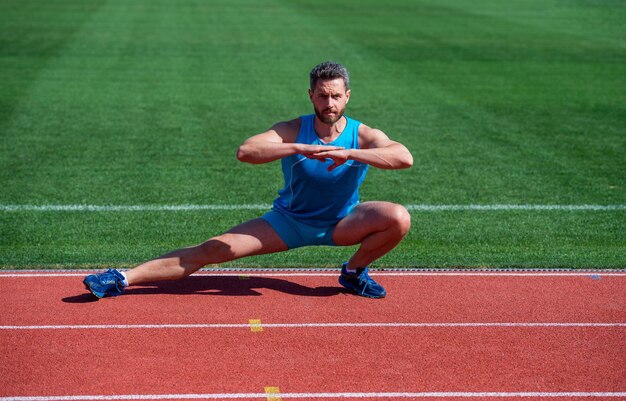 Corridore atletico che fa esercizio di stretching che si prepara per il riscaldamento dell'allenamento mattutino