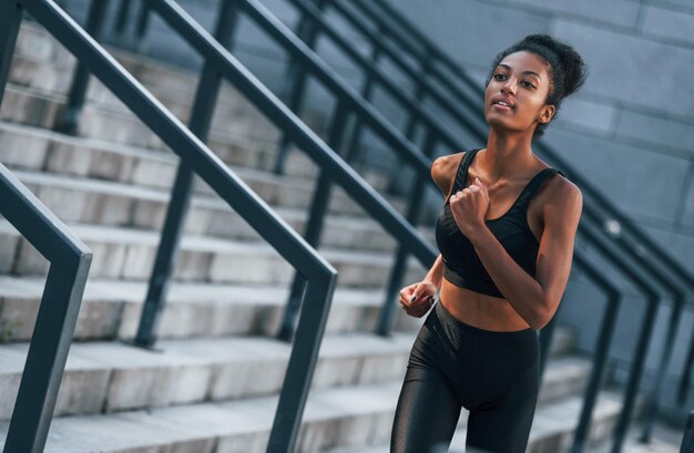 Corridore attivo La giovane donna afroamericana in abiti sportivi si allena all'aperto durante il giorno