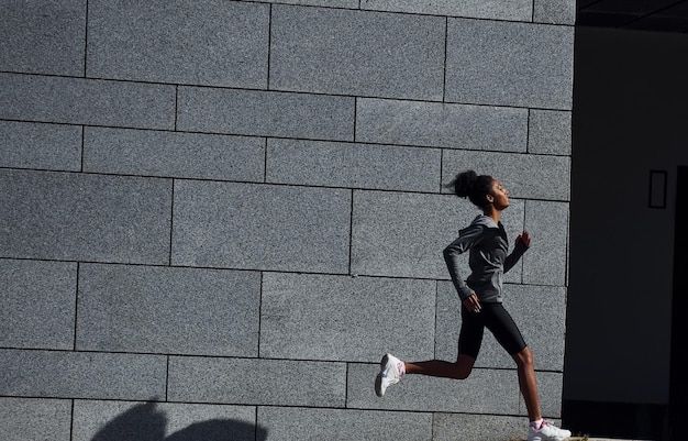 Corridore attivo La giovane donna afroamericana in abiti sportivi si allena all'aperto durante il giorno