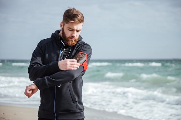 Corridore con il telefono vicino al mare che guarda il telefono