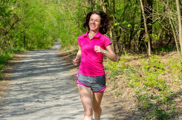 Corridore della donna che pareggia all'aperto nel concetto della foresta, di esercizio, di sport e di forma fisica