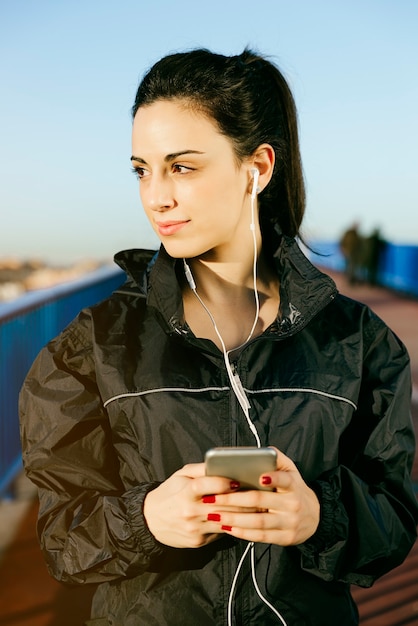 Corridore di giovane donna sta avendo pausa e ascoltando musica durante la corsa in città.