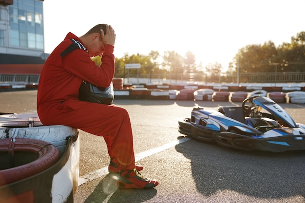 Corridore di gocart frustrato in abbigliamento sportivo che si sente triste e disperato