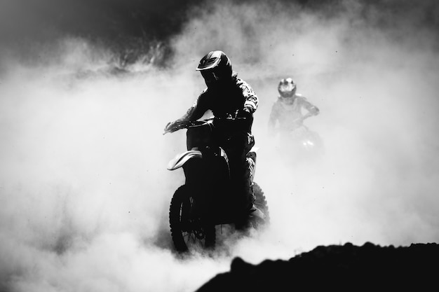 Corridore di motocross che accelera nella pista di polvere, foto in bianco e nero, ad alto contrasto