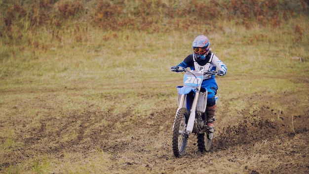 Corridore di motocross su dirt bike in pista sportiva - veloce e pericolo, teleobiettivo