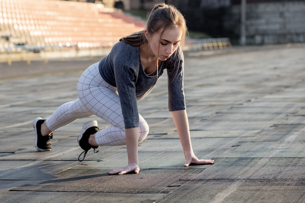 Corridore femminile che allunga le gambe sulla pista da corsa.