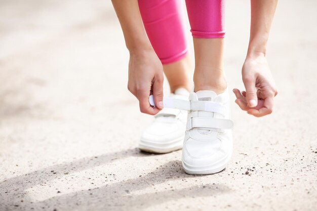 Corridore femminile che lega le sue scarpe che si prepara per una corsa