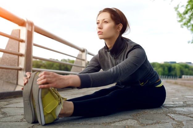 Corridore femminile di Yong con bella figura che fa esercizio di stretching prima di iniziare la sua corsa