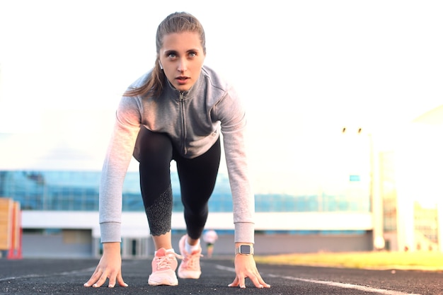 Corridore femminile in attesa dell'inizio sulla linea di partenza nello stadio.