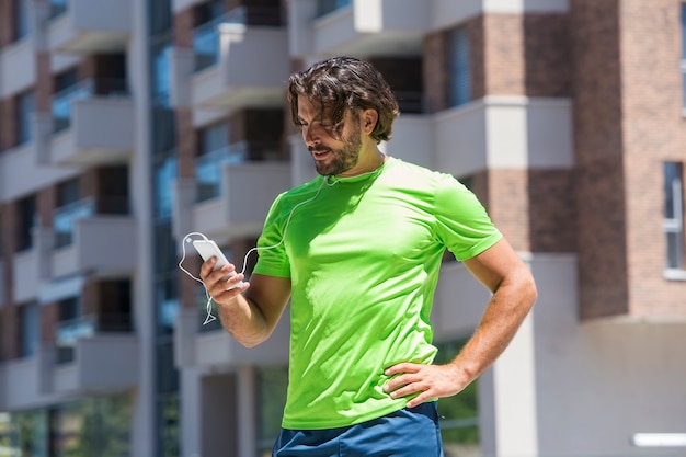 Corridore maschio che utilizza telefono cellulare all&#39;aperto