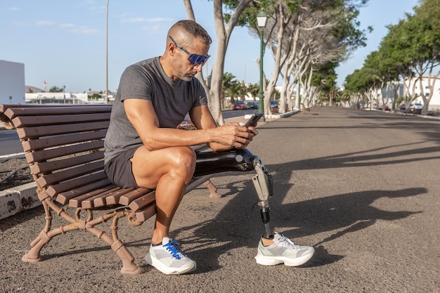 Corridore maschio con disabilità utilizzando lo smartphone su strada