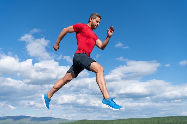 Corridore uomo sportivo correre verso il successo o saltare in alto sullo sfondo del cielo, lo sport.