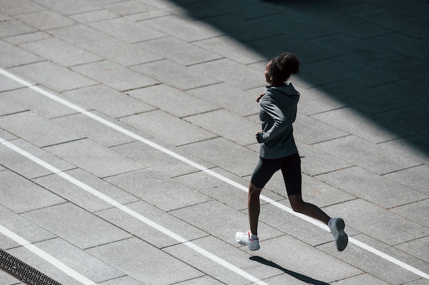 Corridore veloce La giovane donna afroamericana in abiti sportivi si allena all'aperto durante il giorno