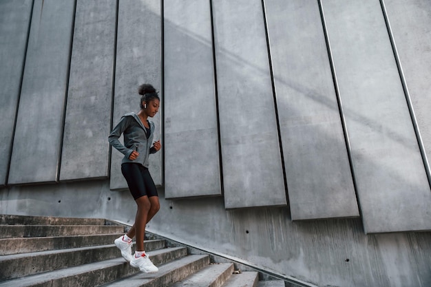 Corridore veloce La giovane donna afroamericana in abiti sportivi si allena all'aperto durante il giorno