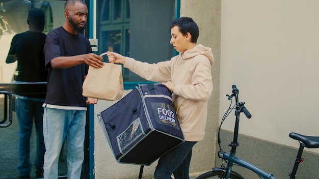 Corriere confuso che consegna un ordine di fastfood sbagliato al cliente, uomo insoddisfatto che si comporta dispiaciuto per il problema del ristorante da asporto. Addetto al servizio di consegna cibo con zaino in bicicletta.