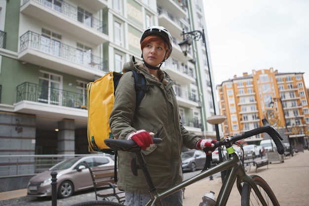 Corriere di consegna femminile che cammina con la sua bicicletta